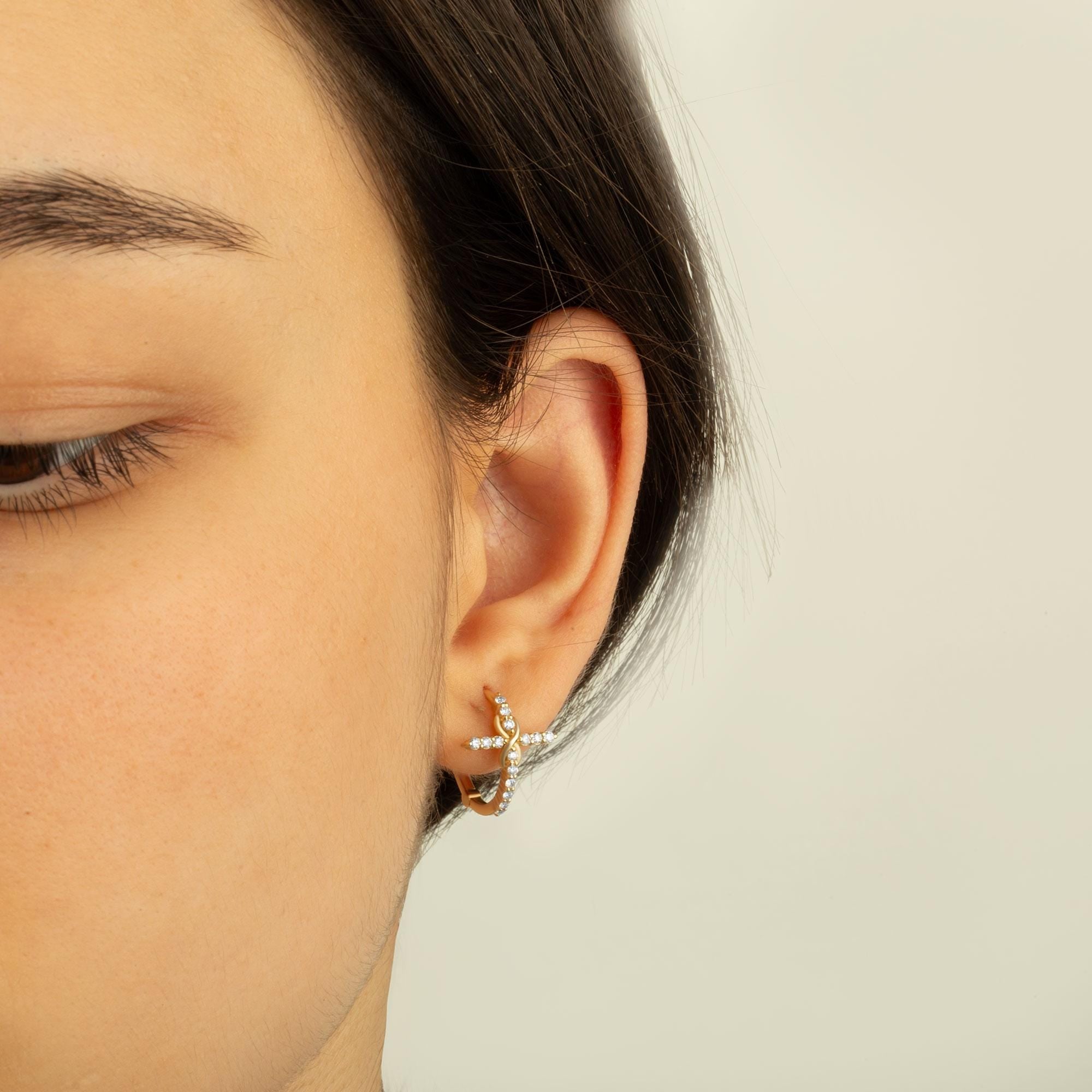 Detailed shot of 14K gold diamond hoop cross earrings highlighting infinity-inspired design and dainty craftsmanship