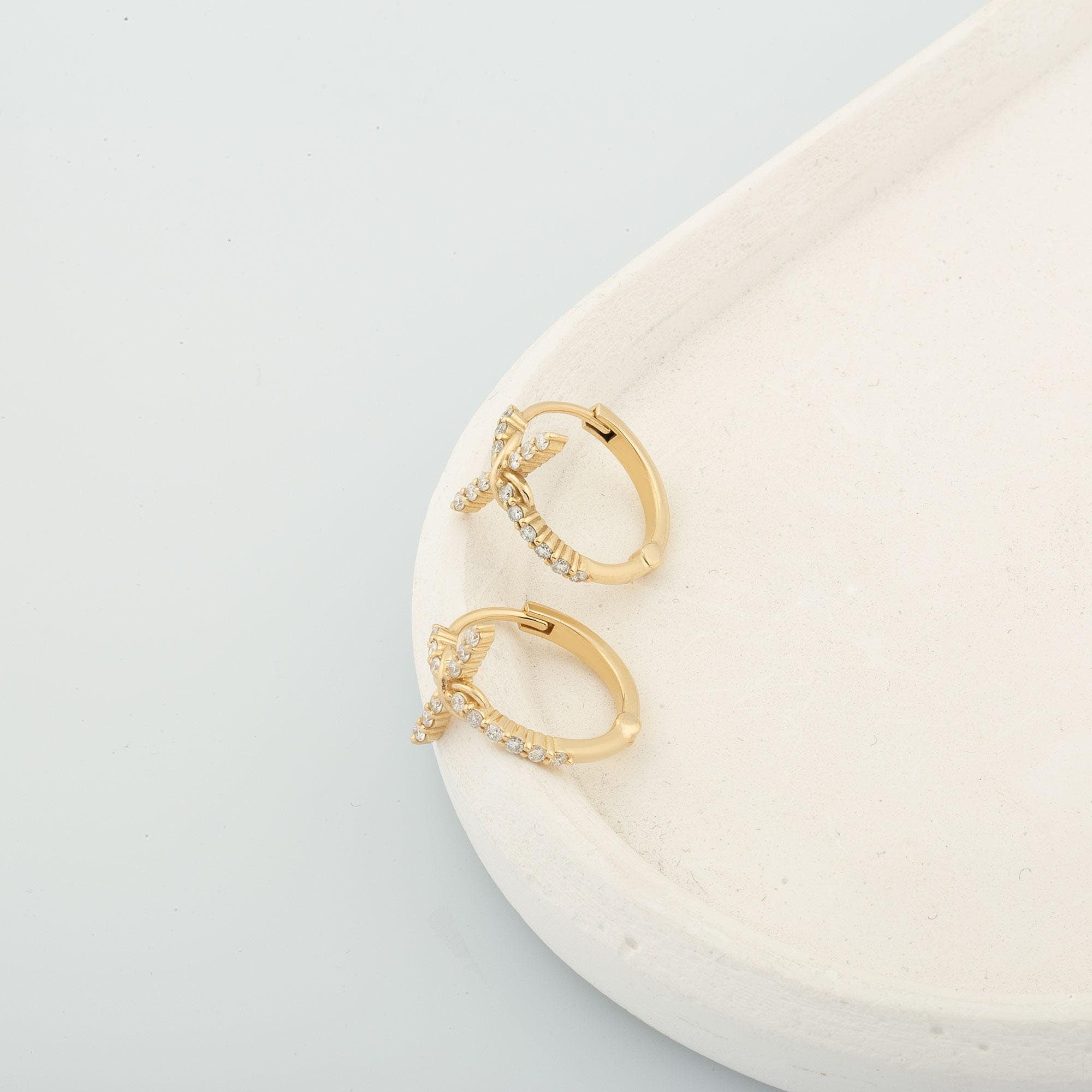 Close-up of 14K gold diamond hoop cross earrings with infinity-inspired design, symbolizing eternal love and timeless elegance.