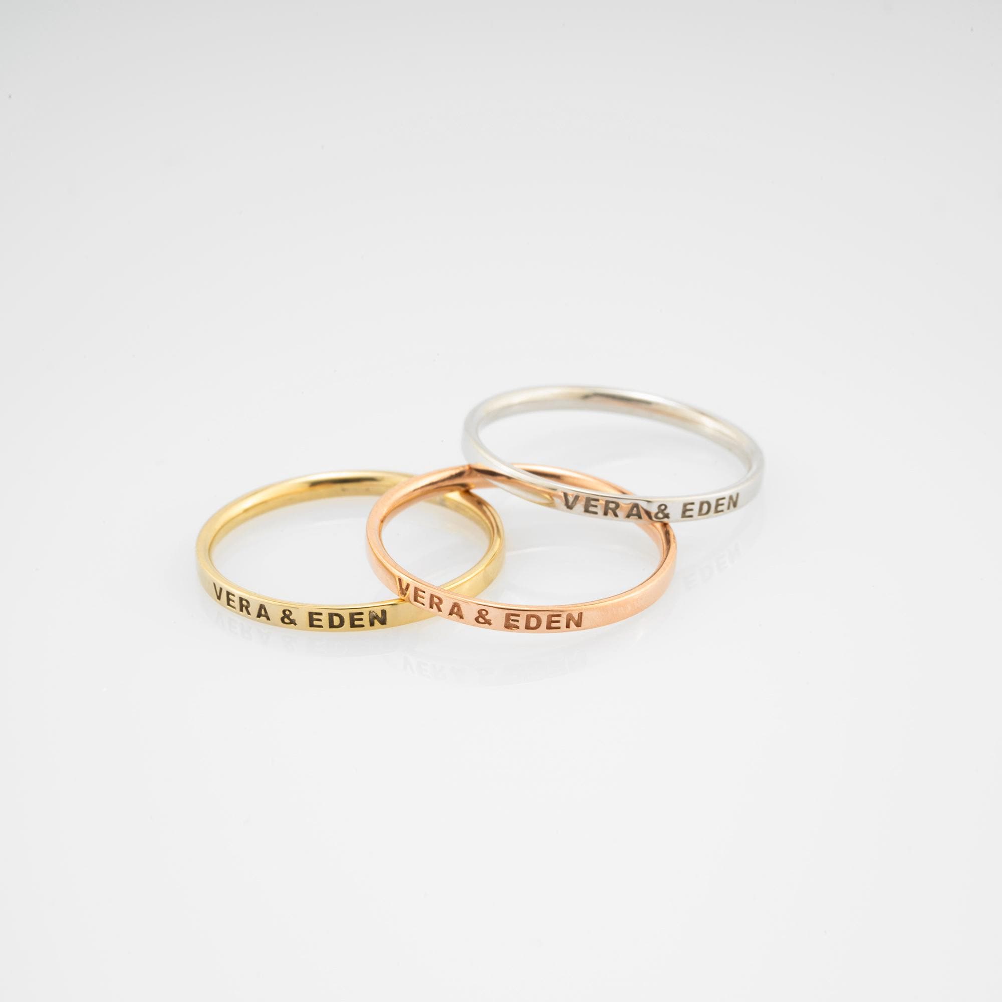 A beautiful display of 14K gold wedding bands in yellow, white, and rose gold, customizable with names, dates, or symbols. These handcrafted rings symbolize love and connection, perfect for celebrating special moments together.