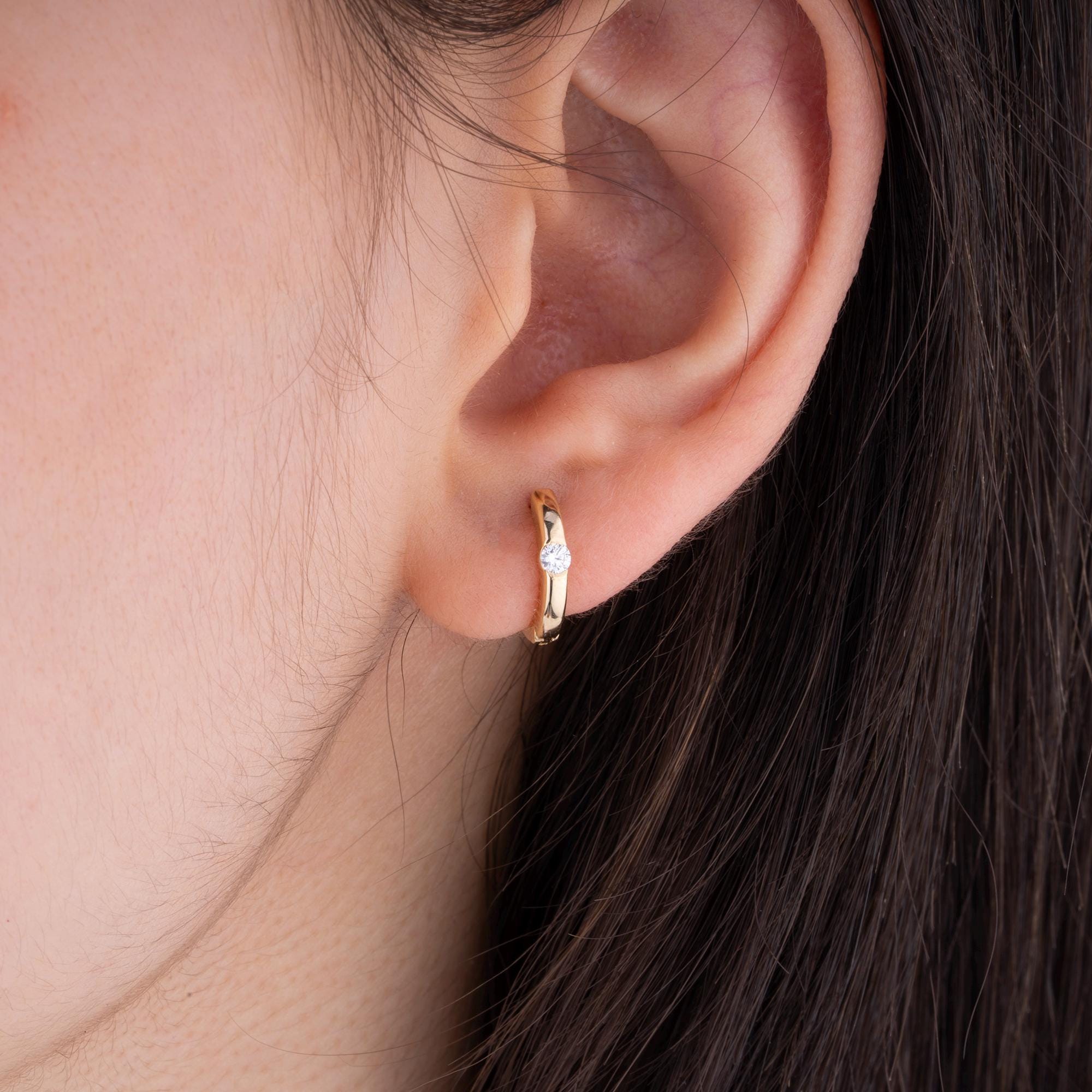 Close-up of solid 14K gold hoop earrings featuring brilliant-cut diamonds, designed for timeless sophistication and luxury.