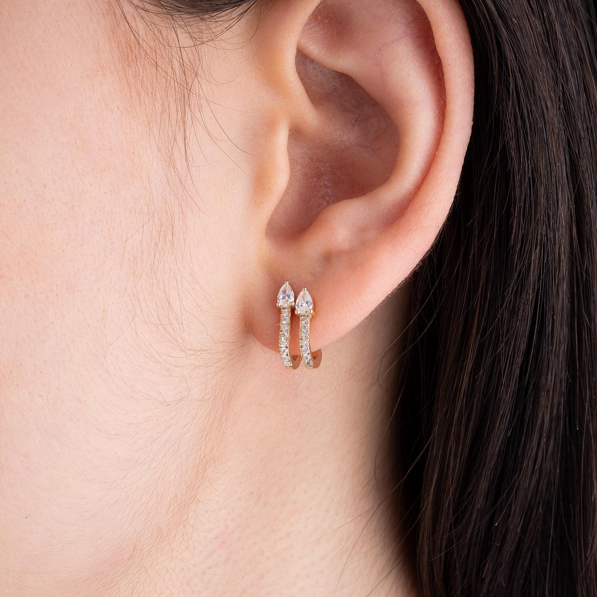 14K gold diamond double huggie earrings designed with a sleek hoop cuff style. These earrings feature round and pear-cut diamonds, offering a radiant and timeless charm.